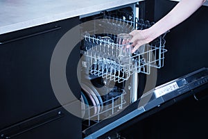 Young woman loads the dishwasher with dirty dishes