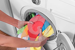 Young woman loads the laundry in the washing machine from the laundry basket before washing.