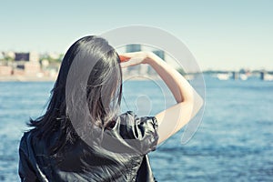 Young woman with long black hair looking at the water in the city