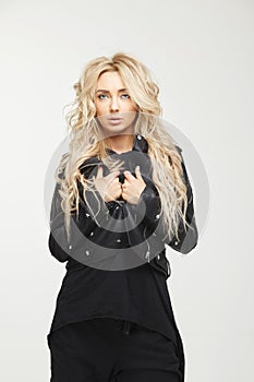 Young woman with long blond hair in stylish black clothes on white background.