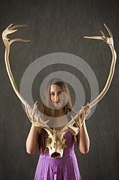 Young woman with long brown hair holding caribou antlers.