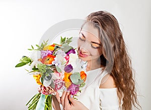 Young woman with long curly hair enjoying flowers bouquet