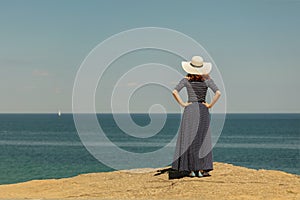 Young woman in a long dark blue skirt on the waterfront near the