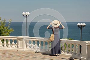 Young woman in a long dark blue skirt on the waterfront near the sea