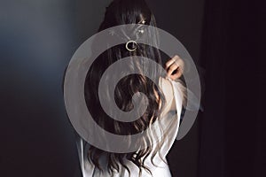 Young woman with long dark hair facing backwards against a dark background