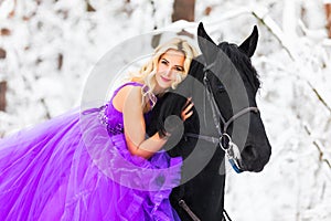 Young woman in long dress riding a horse in winter