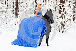 Young woman in long dress riding a horse in winter