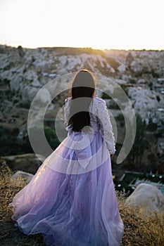 Young woman with long, flowing dress on a hilltop, admiring the majestic mountain range