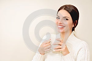 Young woman with long hair and brown eyes drinking coffee or tea from a cup