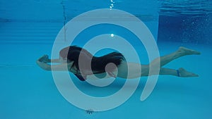 Young woman with long hair diving in pool.