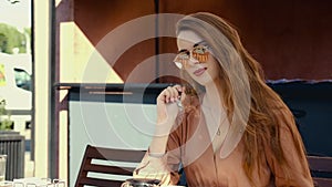 Young woman with long hair eating ice Ñream on cafe terrace in windy day