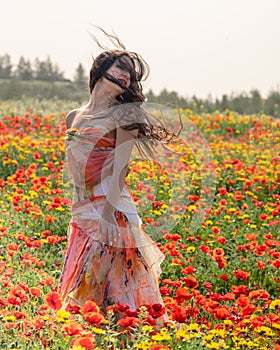 Young woman with long hair happy in the spring poppy field