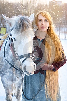 Young woman with long hair with horse in winter