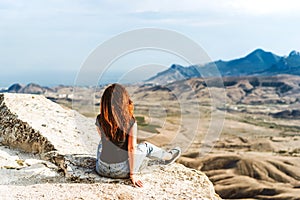 A young woman with long hair and jeans with salt lake in background in Koktebel valley in Crimea. The landscape of sandy hi