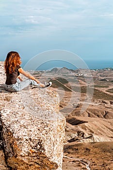A young woman with long hair and jeans with salt lake in background in Koktebel valley in Crimea. The landscape of sandy hi