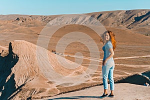 A young woman with long hair stands on the slope of Cape chameleon with an amazing panoramic view of the hills and the sea from ab
