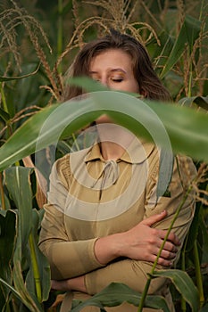 Young happy smiling woman in a green corn field in summer