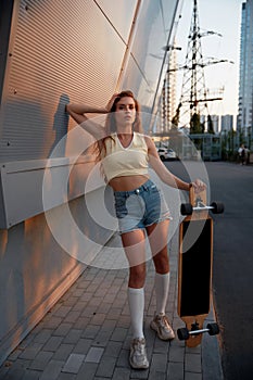 Young woman with longboard standing over cityscape background