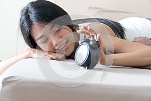 Young woman look alarmclock lying on a bed at home