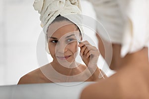 Young woman look in mirror pinch eyebrows in bathroom