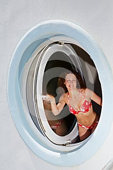 Young woman look out from made in form of porthole