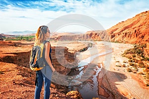 Young woman looking at beautiful landscape. Nature of Morocco view from above. Traveler girl stands on a rock looks up