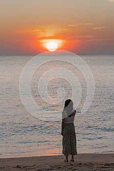 Young woman looking beautiful sunset over horizon at the beach