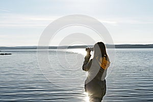Young woman looking through binoculars at birds on lake Birdwatching, zoology, ecology. Research in nature, observation of animals