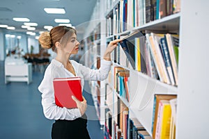 Young woman looking book at the shelf in library