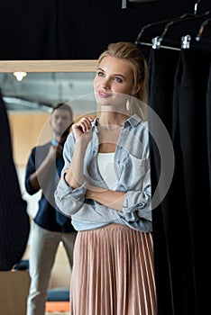 young woman looking at boyfriend trying on necktie