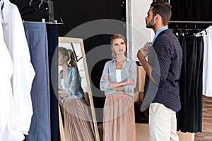 young woman looking at boyfriend trying on necktie