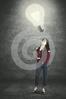 Young woman looking at a bright bulb