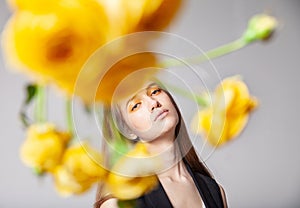 Young woman looking at camera behind yellow flower