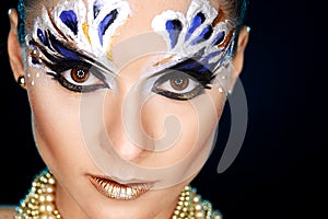 Young woman looking at the camera with fantasy make up face art studio shot.