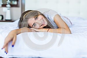 Natural beauty. Young woman looking at camera and smiling while lying on the bed at home