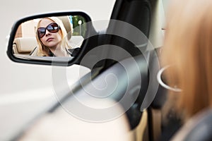 Young woman looking in the car mirror