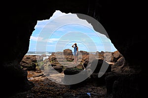 Young woman looking into a cavern of Caves Beach, Australia