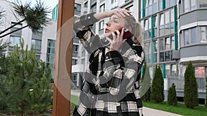 Young Woman Looking Concerned While Talking on the Phone Outside Apartment Building