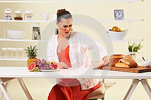 Young woman looking in disgust at a board of breads, wheat