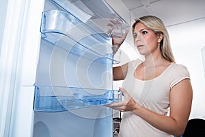 Young Woman Looking In Empty Fridge