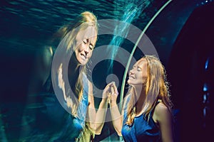 Young woman looking at fish in a tunnel aquarium