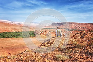 Young woman looking at fortified city. Glaoui Kasbah of Telouet kasbah or ksar in Morocco view from above. Traveler girl