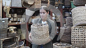 Young woman looking for handmade wickerwork in home decor shop