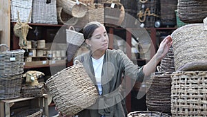 Young woman looking for handmade wickerwork in home decor shop