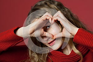 Young woman looking through heart