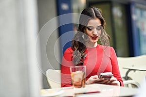 Young woman looking at her smartphone sitting in a cafe photo