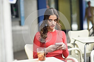 Young woman looking at her smartphone sitting in a cafe photo