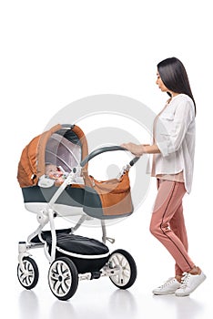 young woman looking at infant baby in baby carriage