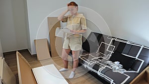 Young woman looking at instructions on how to assemble furniture while standing on the floor home