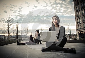 Young woman looking at a laptop and the other sitting in the garden